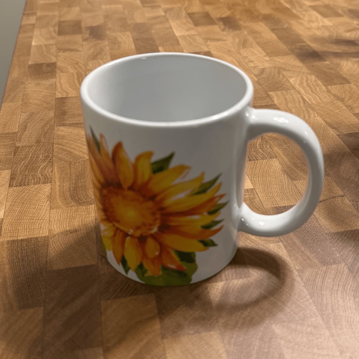 Phone photo of a white mug with a sunflower graphic